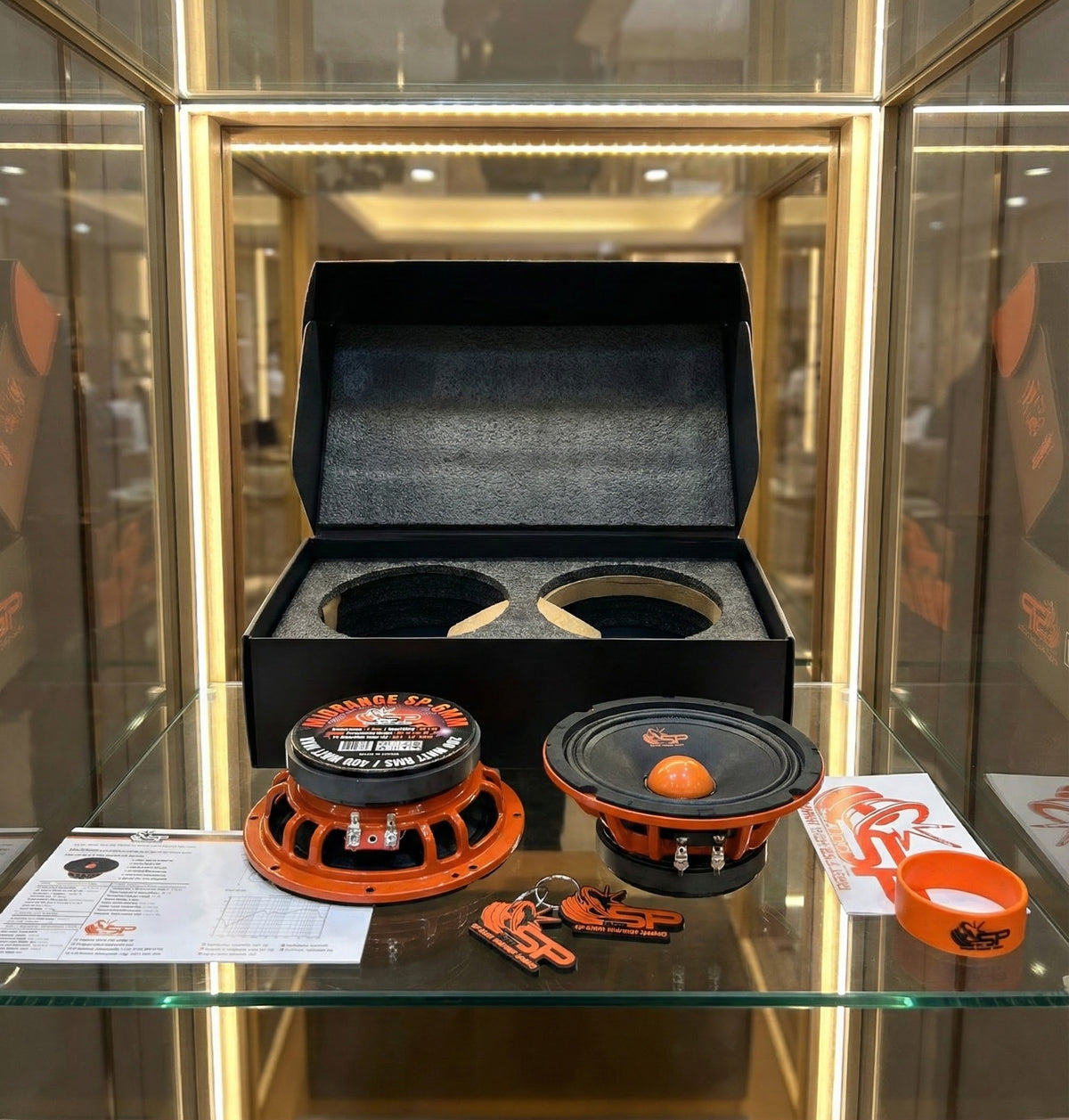 SP 6MM midrange pair with open SP Audio box and accessories in a glass display case